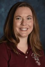 Image of Jamie Baker, who has shoulder-length brown hair and is wearing a crimson NMSU polo