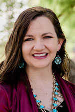 Image of Dr. Shannon Norris, Assistant Professor in the Department of Agricultural and Extension Education at NMSU. She has brown hair and is wearing a leopard-patterned shirt while sitting in front of a black background.