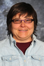 Image of Dawn VanLeeuween, a professor in in the Department of Economics and International Business and has a joint appointment with the Agricultural Experiment Station. She has short brown hair and is wearing glasses, as well as a light-wash denim button-up shirt over a crimson t-shirt.